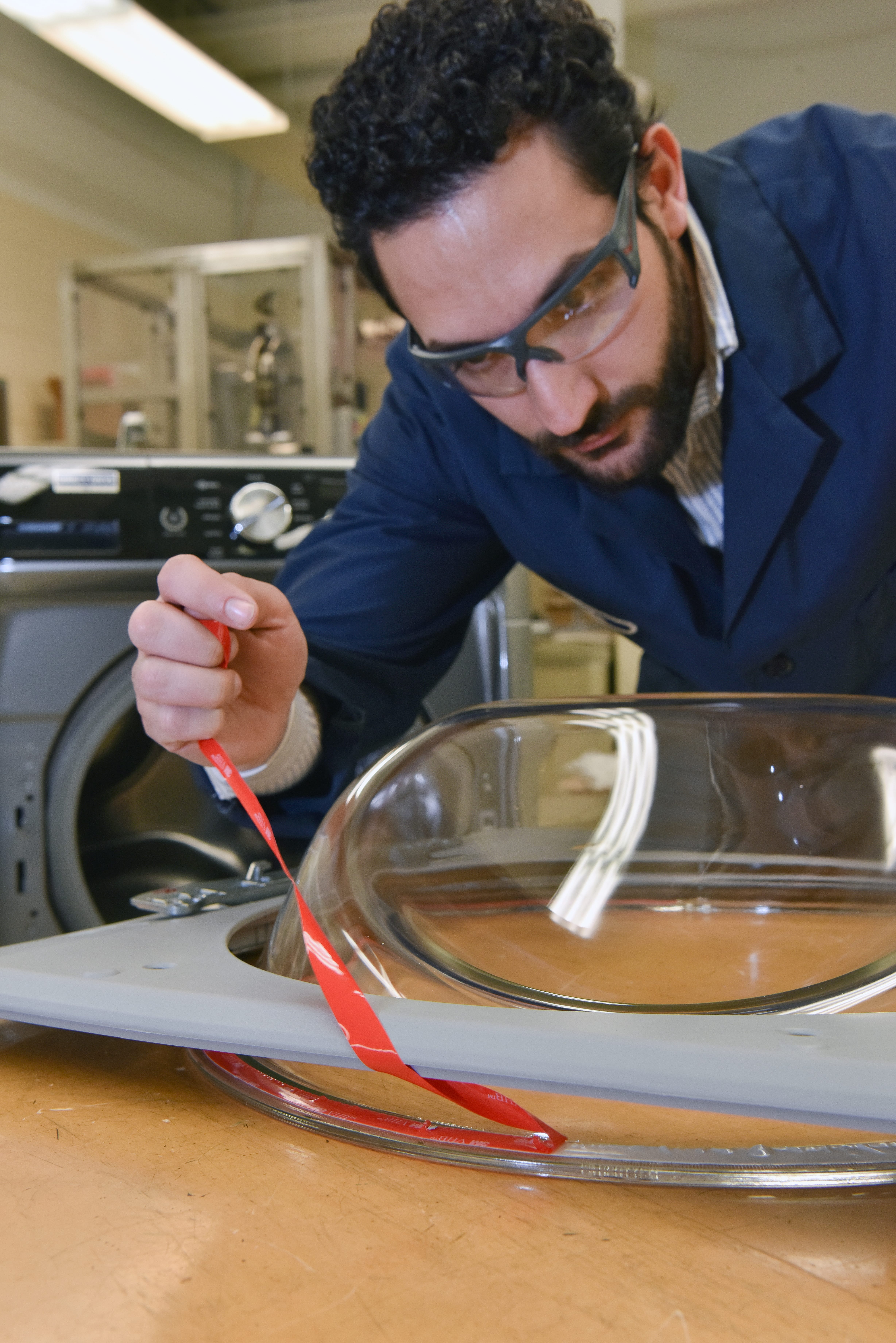 person wearing safety glasses applying vhb tape 