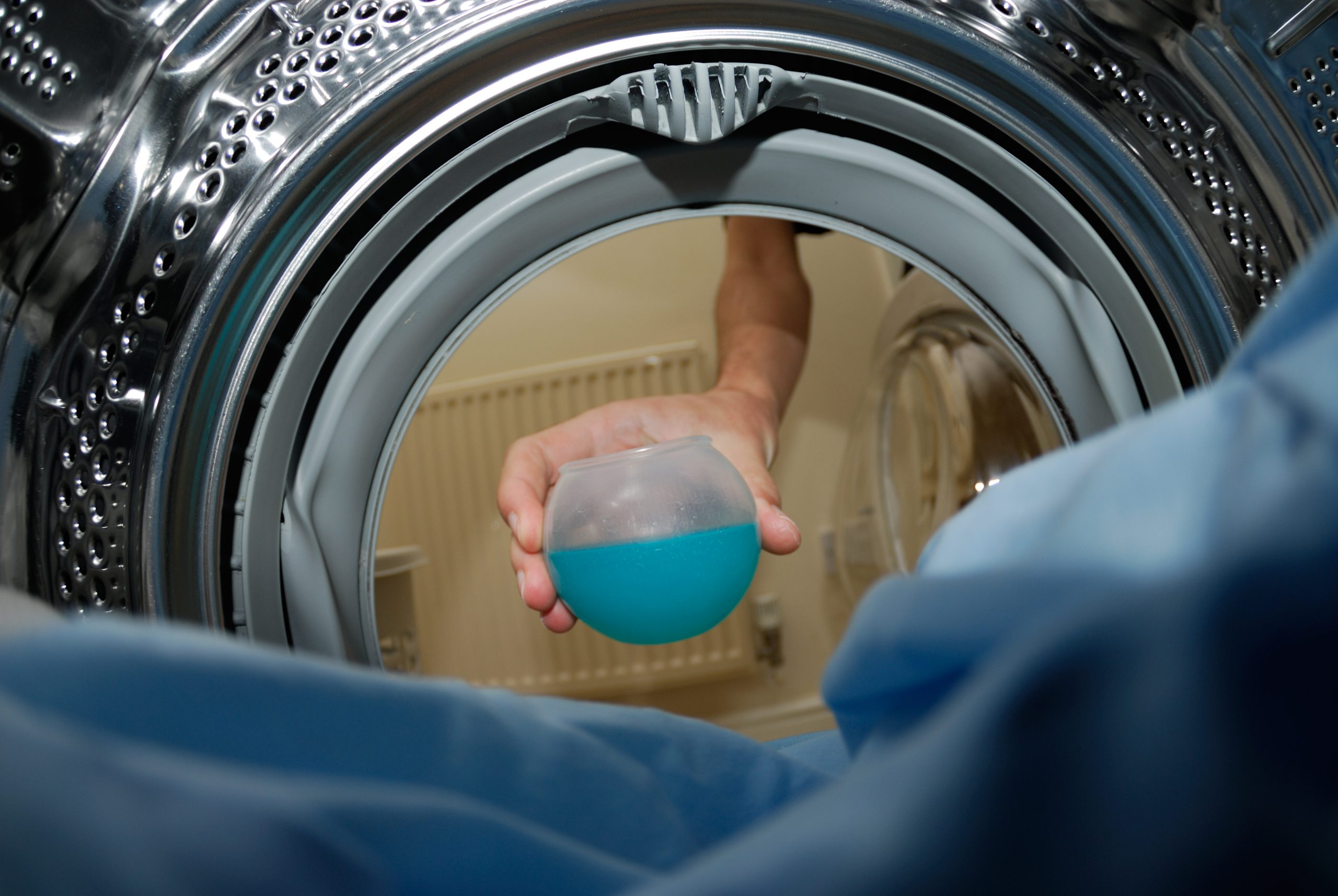 hand putting detergent into washing machine